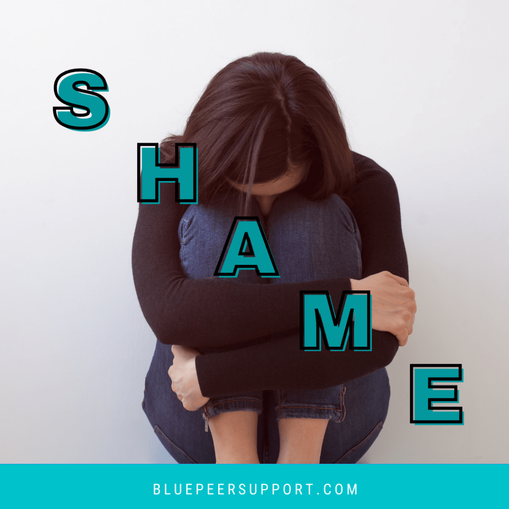 A person sitting on the floor with their arms wrapped around their knees and their head down. The word Shame goes from the top left corner to the bottom right. 